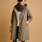 Clara long waterproof raincoat for women with breathable fabric, adjustable waist, removable hood, and belt. Available in Green, Beige, and Black.