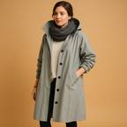 Clara long waterproof raincoat for women with breathable fabric, adjustable waist, removable hood, and belt. Available in Green, Beige, and Black.